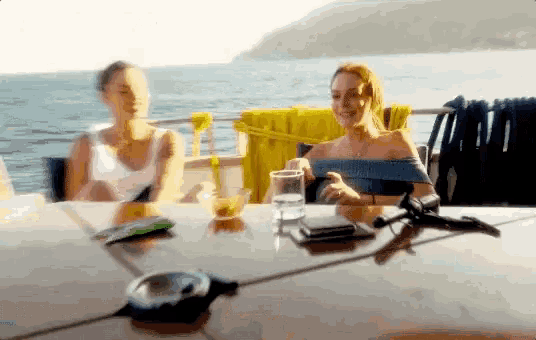 two women sitting at a table with a glass of water
