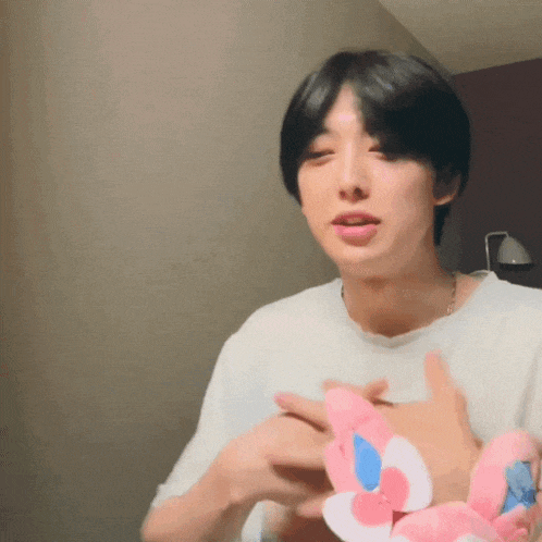 a man in a white shirt is holding a pink and blue flower