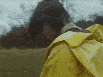 a person wearing a yellow raincoat is walking in the rain