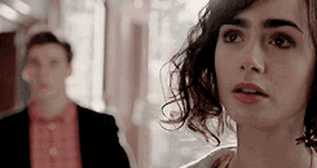 a man and a woman are standing next to each other and the woman is looking at the man .
