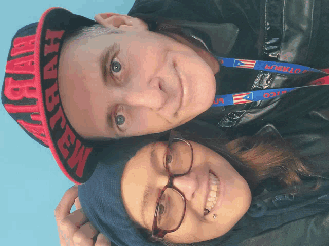 a man and a woman are posing for a picture and the man is wearing a hat that says hawaii on it
