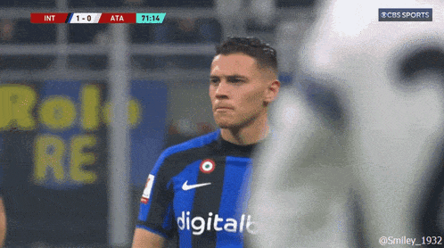 a soccer player stands in front of a digital advertisement