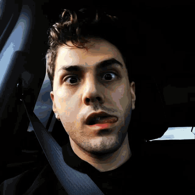 a man in a car with a seat belt around his neck making a funny face