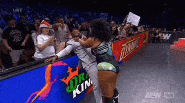 a female wrestler is fighting a man in a suit in front of a crowd .