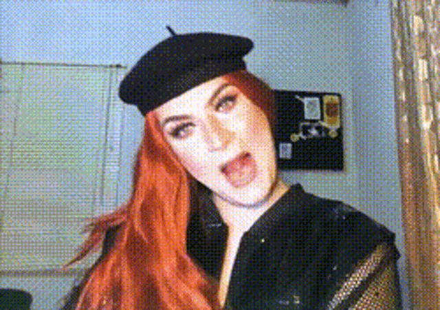 a woman with red hair wearing a black hat