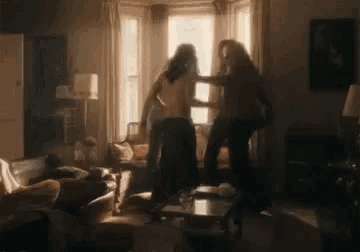 two people are fighting in a living room .