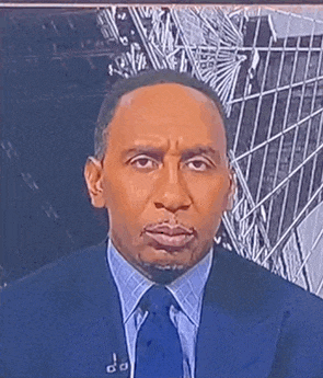 a man in a suit and tie is making a funny face while looking at the camera .