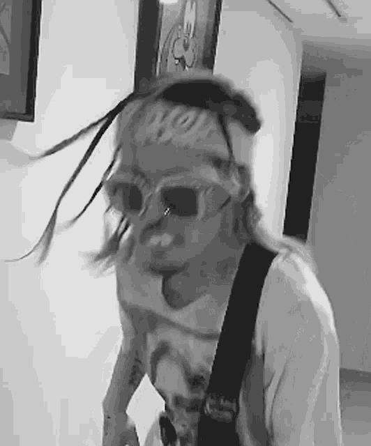 a black and white photo of a man wearing sunglasses and a bandana on his head .