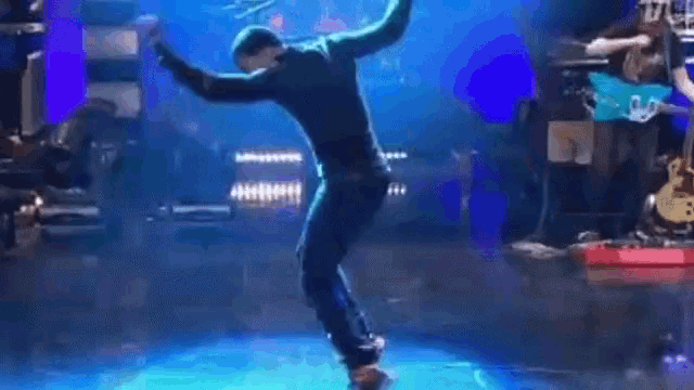 a man is walking on a stage in front of a blue background .