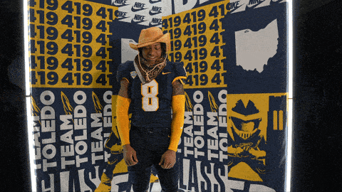 a man wearing a cowboy hat is standing in front of a wall that says nike
