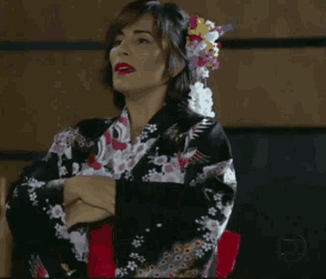 a woman in a kimono stands in a messy room