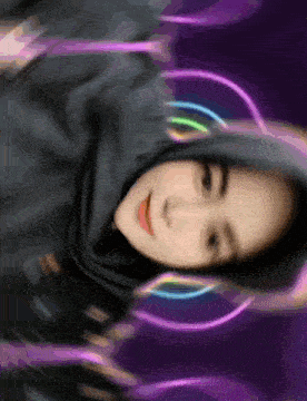a woman wearing a hijab and neon headphones looks at the camera