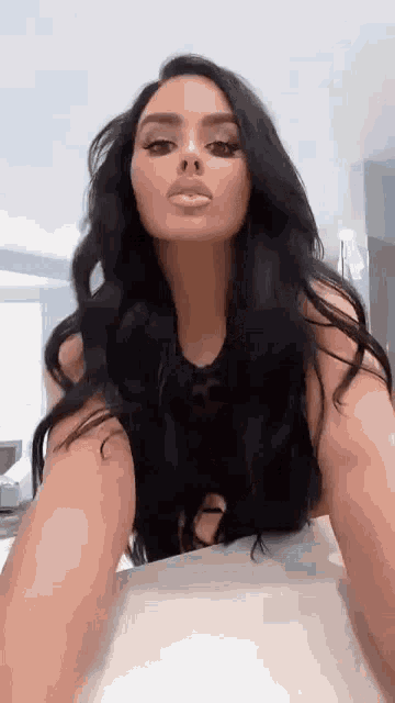 a woman with long black hair is taking a selfie with her phone .