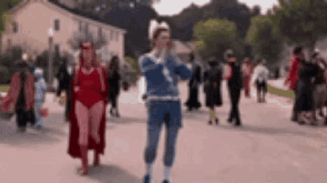 a group of people in costumes are walking down a sidewalk .