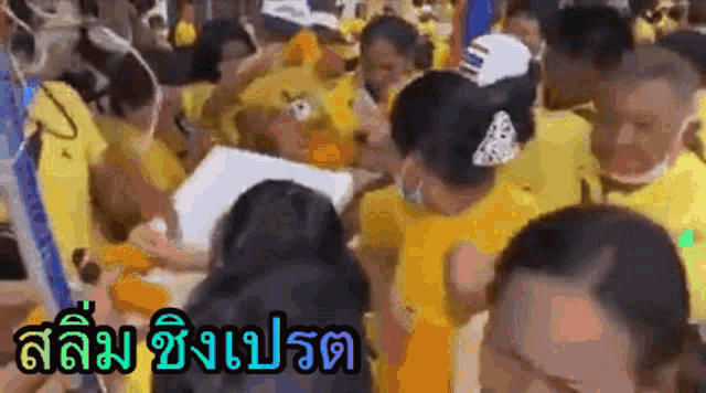 a crowd of people in yellow shirts are gathered around a table with a sign that says ' slum '