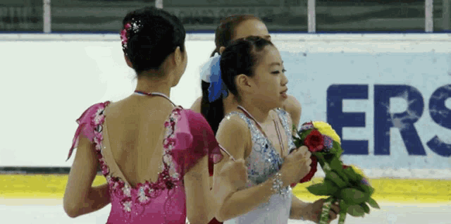 a woman holding a bouquet of flowers in front of a sign that says " ers "