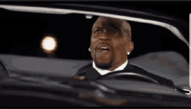 a man in a suit and tie is driving a car at night