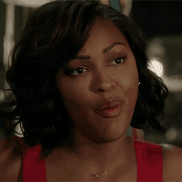 a woman in a red tank top and necklace is making a funny face