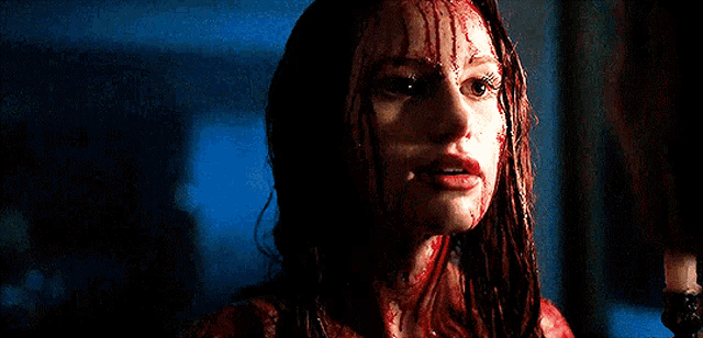 a woman with blood on her face is smiling in a dark room