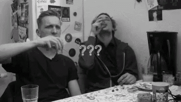 two men are sitting at a table with a microphone in their mouths .