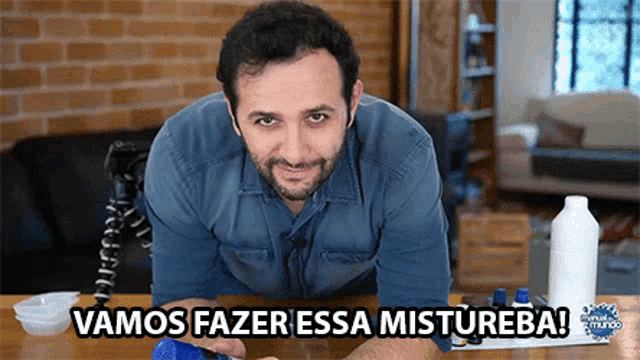 a man is sitting at a table with the words vamos fazer essa mistureba