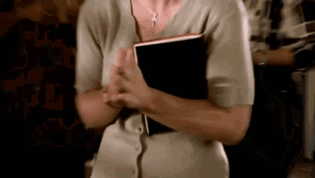 a woman in a tan sweater is holding a book in her hands