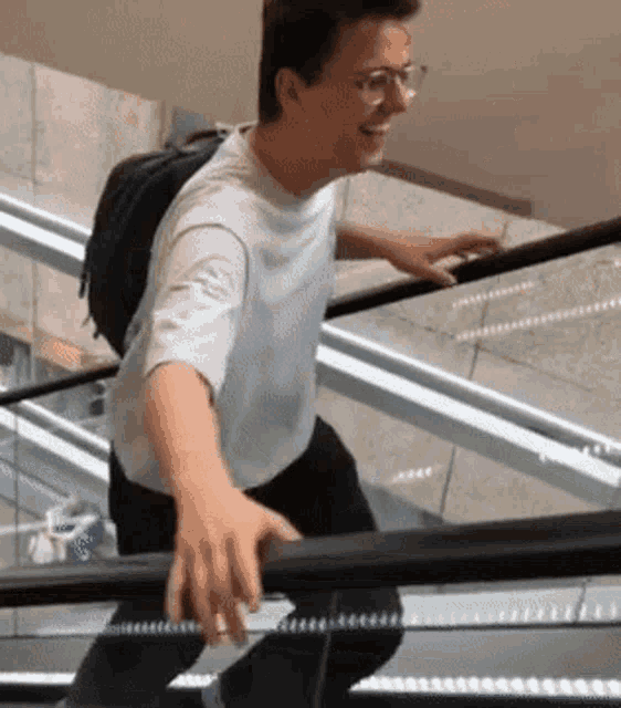 a man with glasses is riding an escalator with his hand on the railing