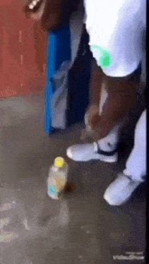 a person is kicking a bottle of water on the floor