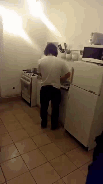 a man in a white shirt is standing in a kitchen next to a refrigerator