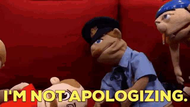 a group of puppets are sitting on a red couch and one of them is a police officer .