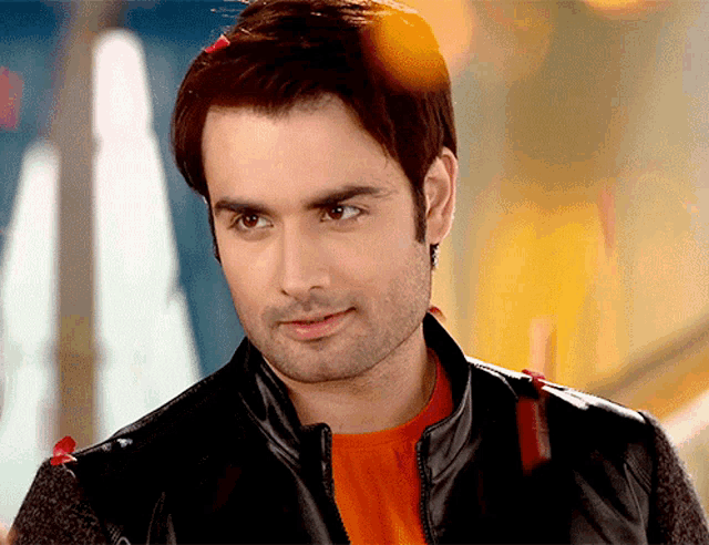 a man wearing a black jacket and an orange shirt