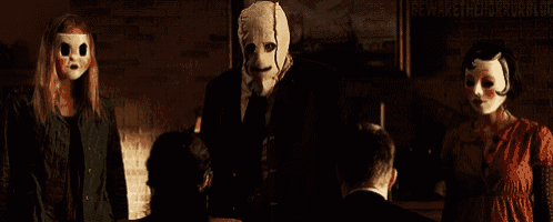a group of people wearing masks are standing next to each other in a dark room