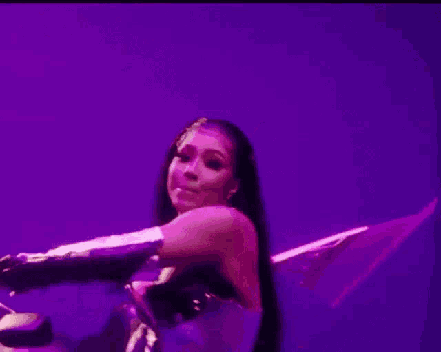 a woman is standing in front of a purple wall holding a skeleton .