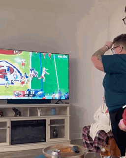 a man is watching a football game on a tv