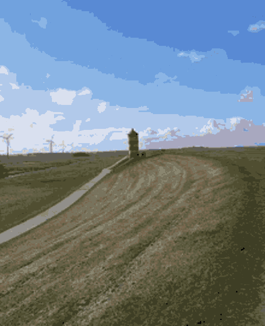 a grassy field with a tower in the distance