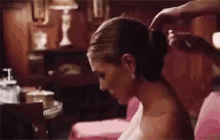 a woman is getting her hair done by a man while sitting on a couch .