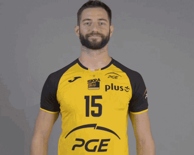 a man with a beard is wearing a yellow and black pge shirt
