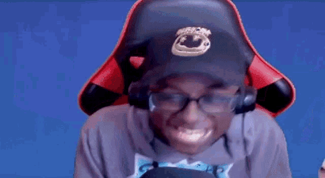 a young man wearing headphones and a hat is sitting in a red chair .