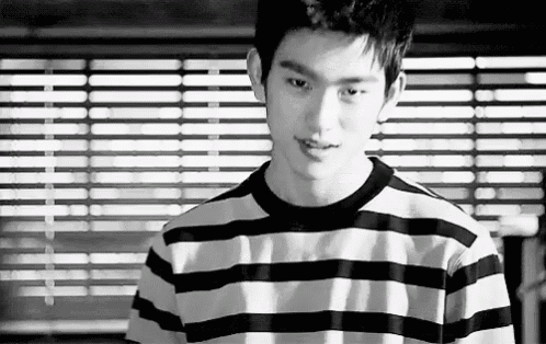 a young man wearing a striped shirt is standing in front of a window .