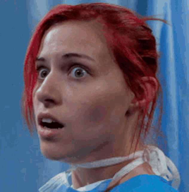 a woman with red hair is wearing a blue scrub top