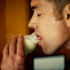 a man is drinking milk from a bottle that says ' milk ' on the label