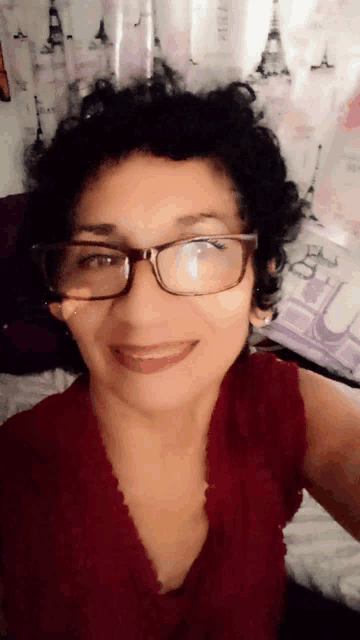 a woman wearing glasses and a red top smiles