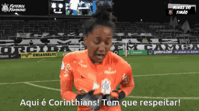 a female soccer player stands on a field with the words aqui e corinthians tem que respeitar