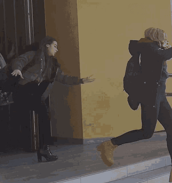 a woman in a brown jacket is standing on a set of steps