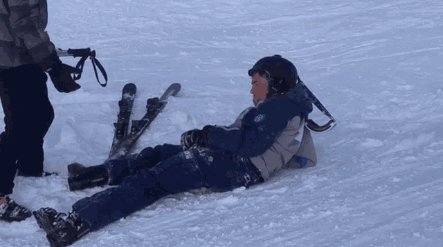 a man laying in the snow with his skis on his back