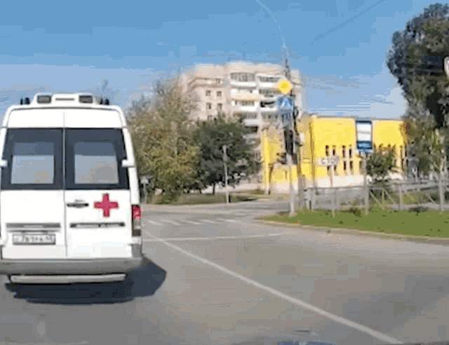 a white ambulance with a red cross on the side is driving down a street