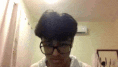 a man wearing glasses and a white shirt is looking at the camera in a room .