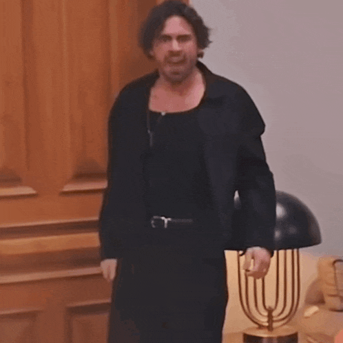 a man in a black jacket stands in front of a lamp