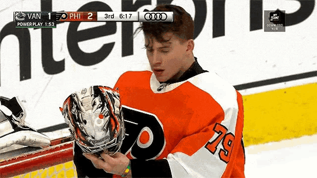 a hockey player with the number 79 on his jersey is looking at his helmet