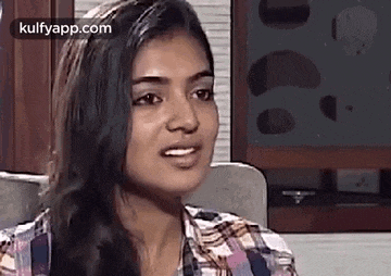 a woman in a plaid shirt is making a funny face while sitting in front of a television .